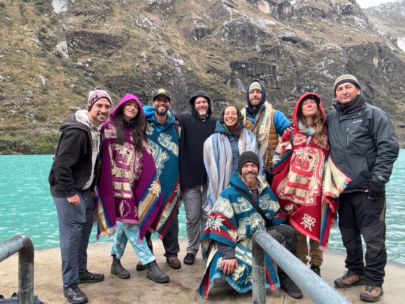 Full Sacred Ways group in colorful ceremonial ponchos at Heaven's Gate alpine lake