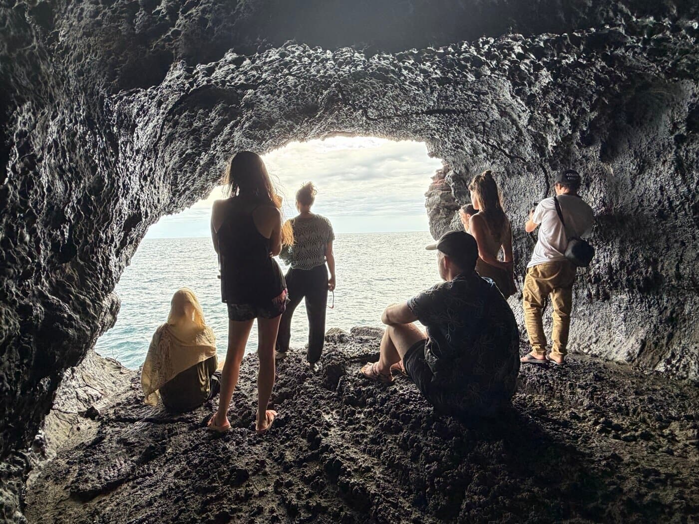 Sacred Ways group silhouetted in a Big Island sea cave looking out at the ocean