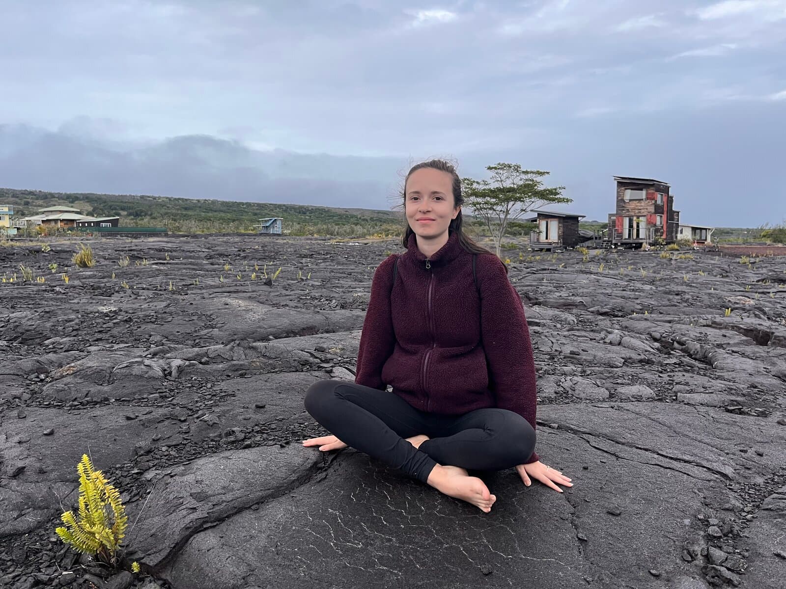 Retreat participant meditating cross-legged on a Big Island lava field